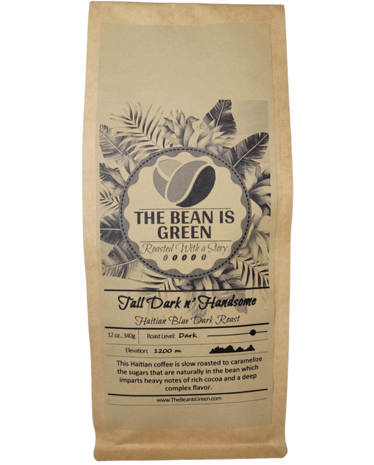 Brown kraft bag with The Bean Is Green grey-wash tropical logo. Tall Dark n' Handsome - Organic Haitian Blue Dark Roast Whole Bean Coffee. Elevation 1200m with graph shown. This Haitian coffee is slow roasted to caramelize the sugars that are naturally in the bean which imparts heavy notes of rich cocoa and a deep complex flavor. - website = www.thebeanisgreen.com